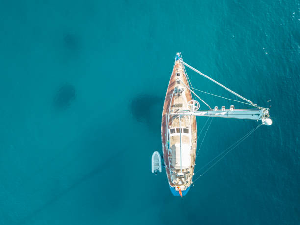 Aerial bird's eye view drone of boat docked in mediterranean tropical beach with turquoise - sapphire waters